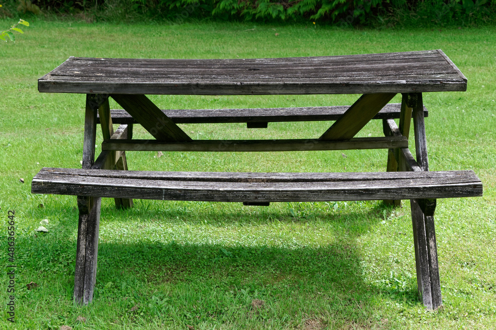 A rustic, wooden picnic table sits on the grass