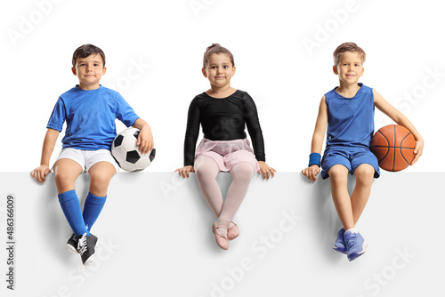 Ballerina girl, boys with football and basketball sitting on a blank panel