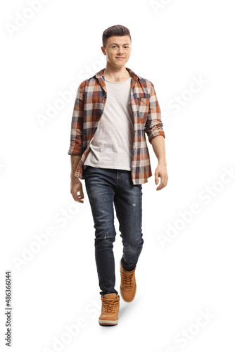 Full length portrait of a guy in jeans and checkered shirt walking towards camera