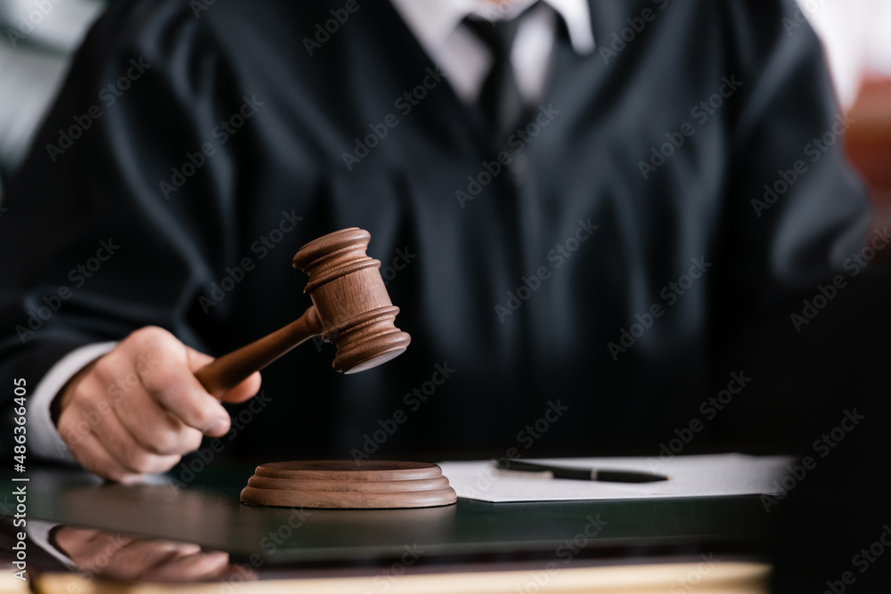 partial view of blurred judge in robe holding gavel in court - obrazy, fototapety, plakaty 