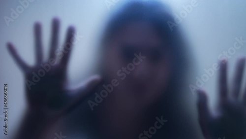 Defocused woman stuck behind glass feeling trapped photo