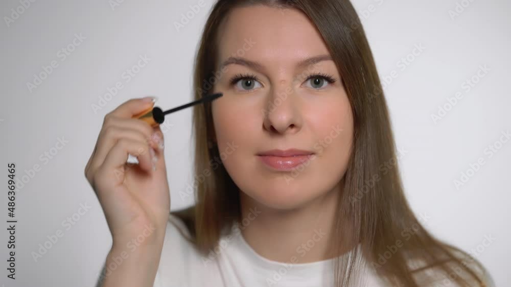 Young beautiful woman doing makeup. The girl applies mascara with make up brush. Young beautiful woman doing makeup. The girl applies mascara with make up brush.