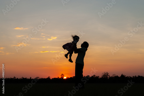 silhouette of mother raising her child at sunset