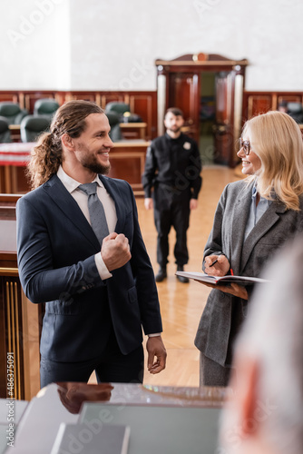 Obraz na plátně justified businessman showing success gesture near smiling advocate and blurred
