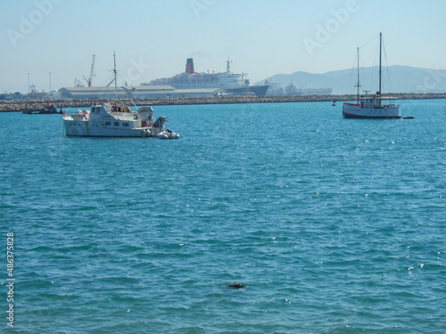 Some fishing boats and sailboats in front of the container port in algeciras spain. In the background you can see a steam ferry © Luca Schmidt