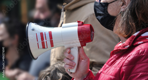 Mulher a falar através de um megafone no meio de uma multidão - manifestação - mão a segurar no megafone - máscara na cara - pandemia - COVID-19 photo
