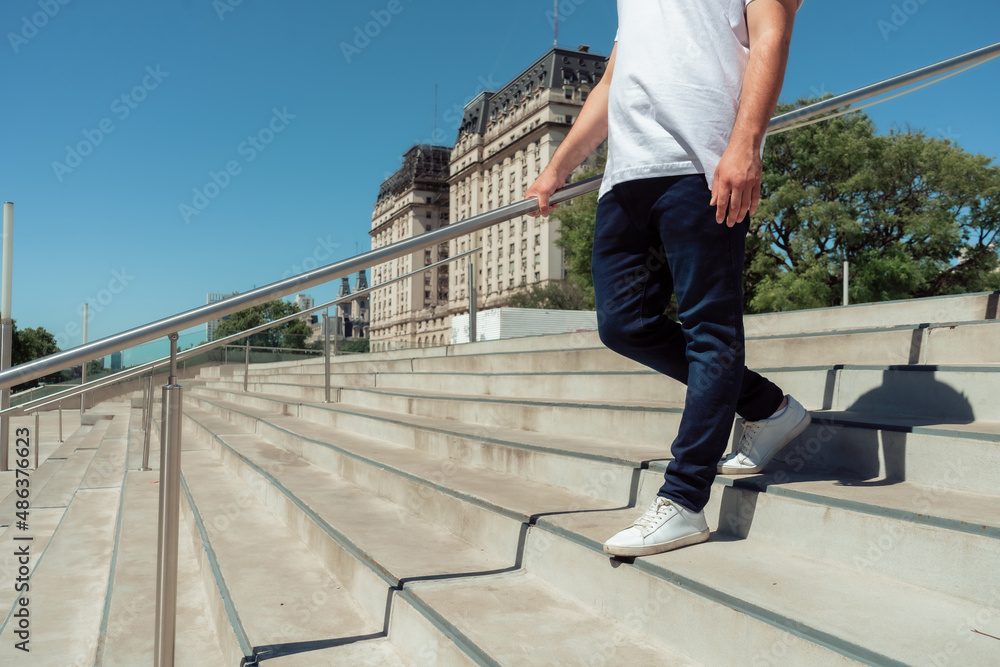 unrecognizable latino man with a jean and white sneakers going down a cement stairs. Horizontal orientation. unrecognizable latino man with a jean and white sneakers going down a cement stairs. Horizontal orientation.