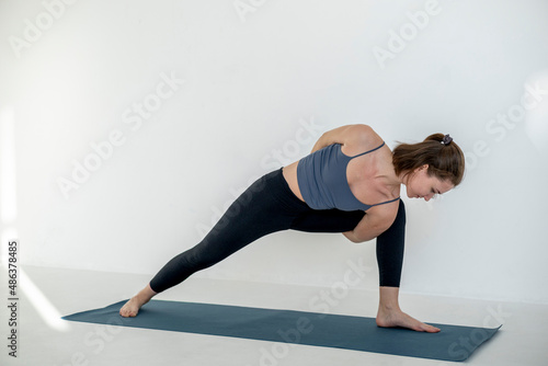 Beautiful girl practicing asana on blue yoga mat. Healthy lifestyle. Sport and fitness.