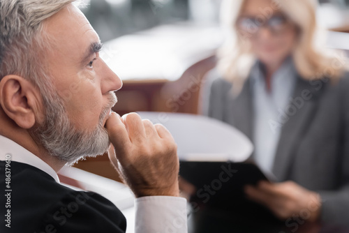 Canvas Print selective focus of senior judge thinking near blurred attorney in courtroom