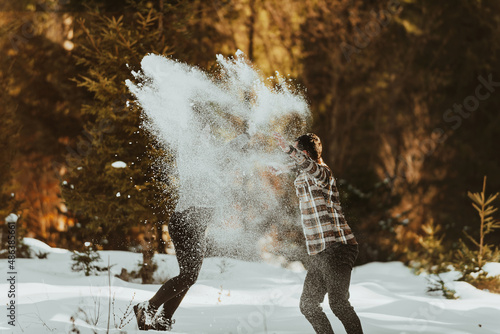 Snowball fight. Winter couple having fun playig in snow outdoors. Young joyful happy lovers. Selective focus. photo