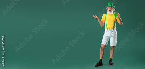 Senior man with glass of beer on green background with space for text. St. Patrick's Day celebration