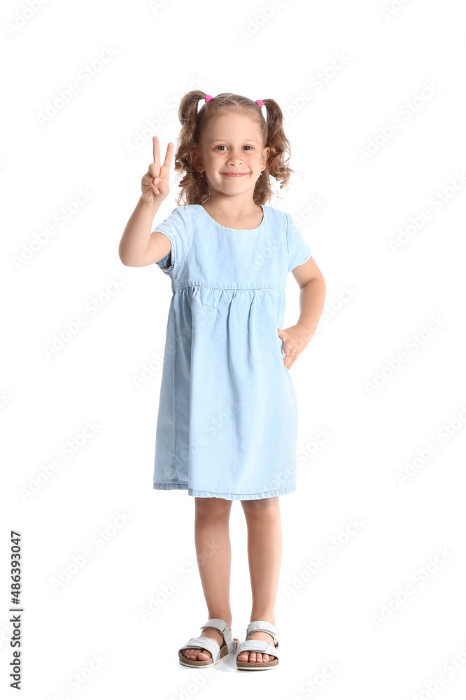 Funny little girl in blue dress showing victory gesture on white background Funny little girl in blue dress showing victory gesture on white background