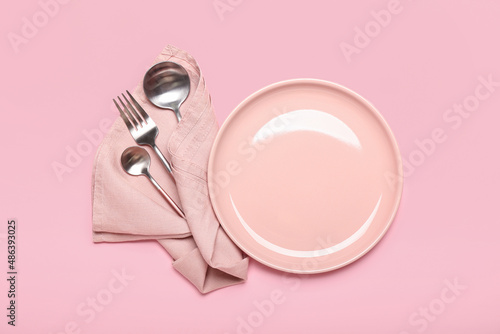 Plate and set of cutlery on color background