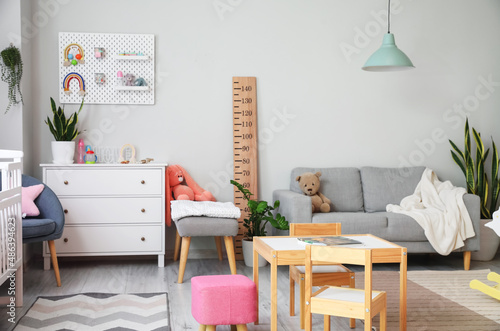 Interior of stylish children's room with commode, sofa and pegboard