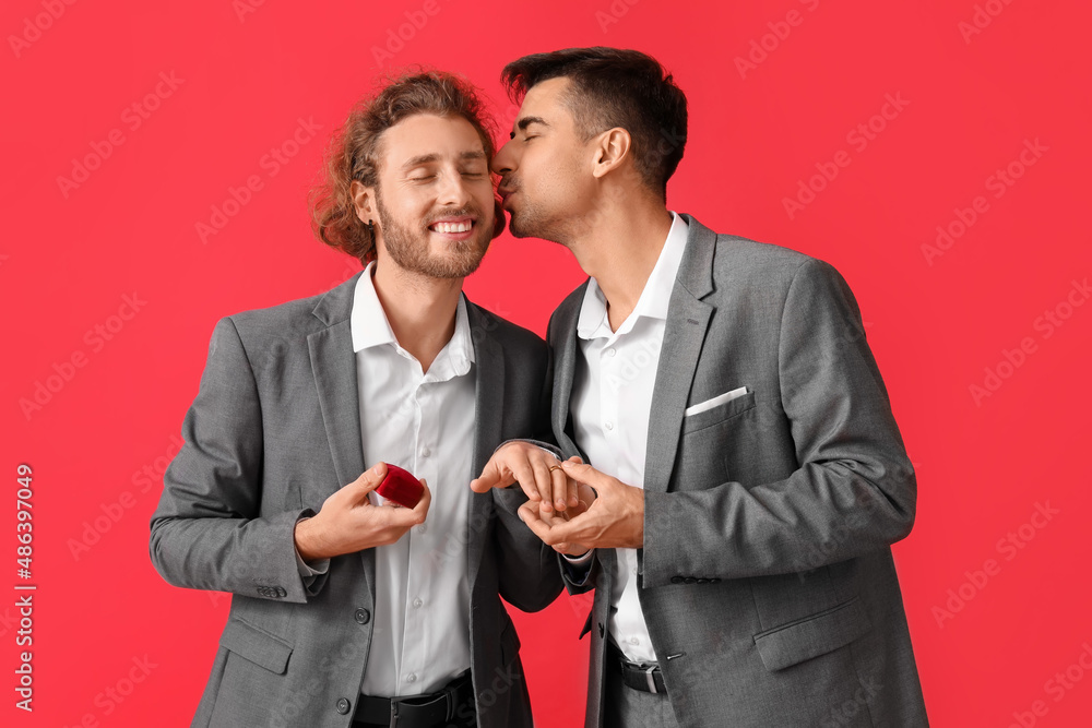 Happy engaged gay couple on red background Happy engaged gay couple on red background