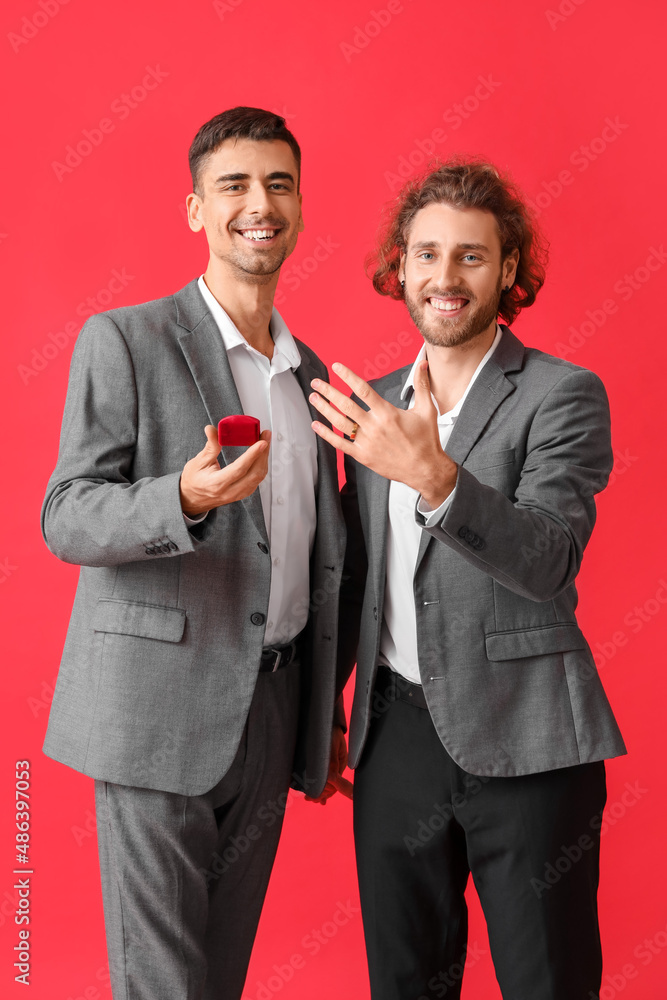 Happy engaged gay couple on red background Happy engaged gay couple on red background
