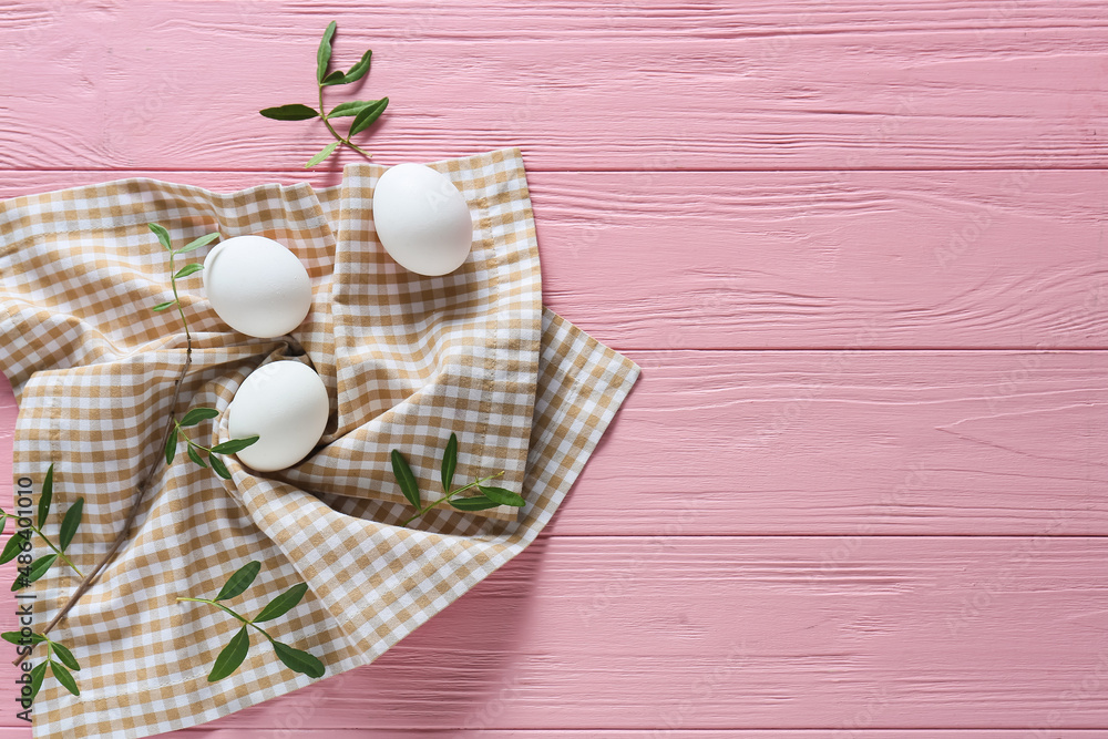 Easter eggs and green branches on color wooden background