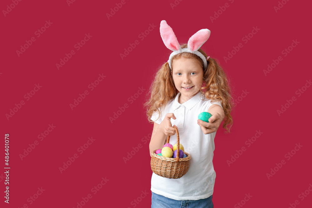 Funny little girl with bunny ears and Easter basket on red background