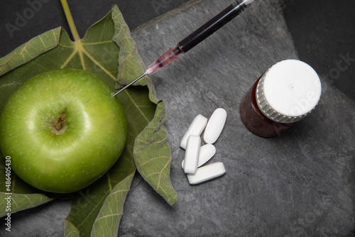 Green apple with syringe and medicine on a stone background. High quality photo