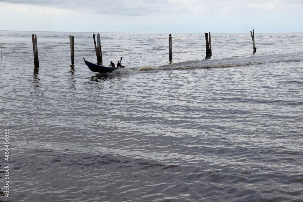 boat speeding cloudy rainy storm day rolling sea water wave on murky dirty rock sand shore jetty column boat speeding cloudy rainy storm day rolling sea water wave on murky dirty rock sand shore jetty column
