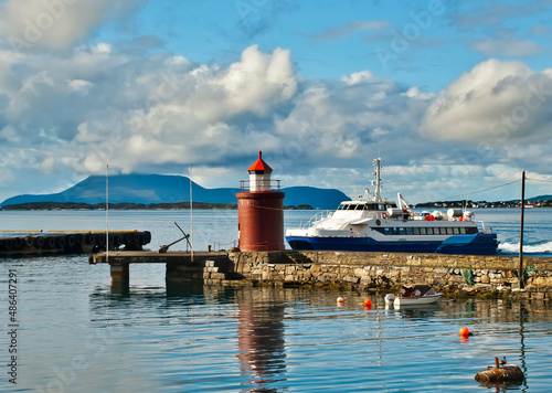 Pleasure motorboat near a marina with lighthouse, Alesund, Norway