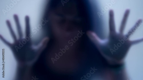 Silhouette woman behind glass suffocating from mental emotional pain concept defocused shot