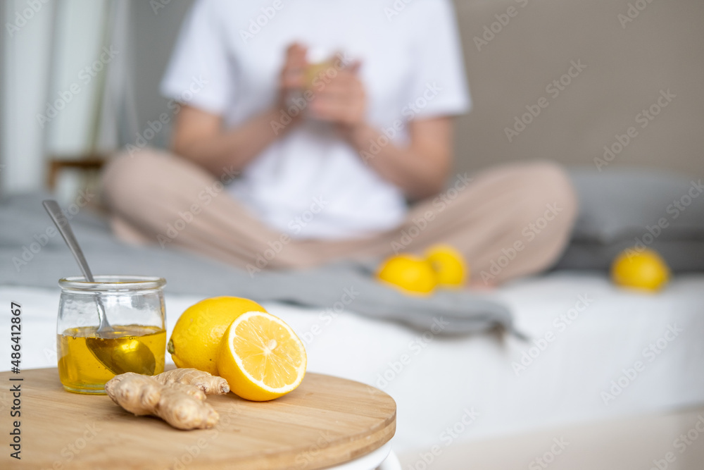 The girl in the background drinks healthy water with lemon. Lemon, honey and ginger for health and immunity. High quality photo