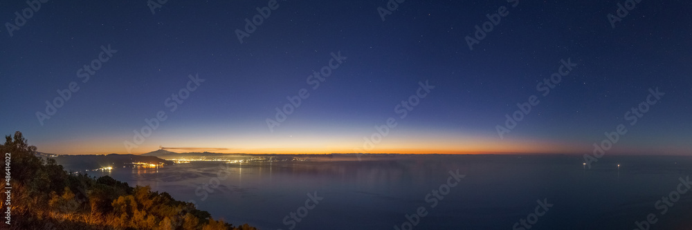 Panorama before Eruption of Etna volcano with smoke in front of the mediterranean sea after sunset with stars on February 10 2022 , Sicily, Italy