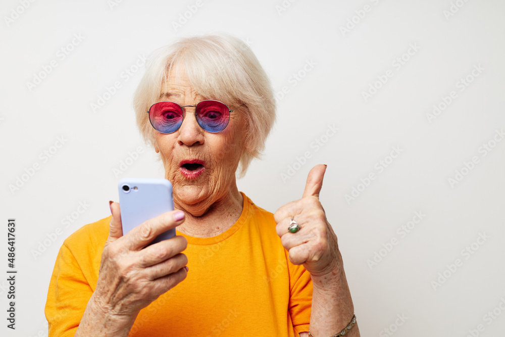 elderly woman in fashionable glasses with a smartphone in hand cropped view