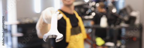 Uniformed car repairman holds wrench in car repair shop photo