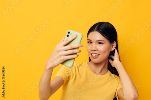 Portrait Asian beautiful young woman in a yellow t-shirt looking at the phone posing Lifestyle unaltered