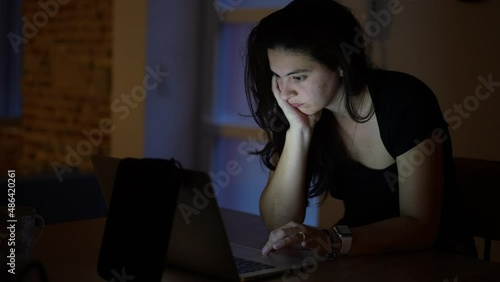 Woman browsing internet in front of laptop screen at night photo