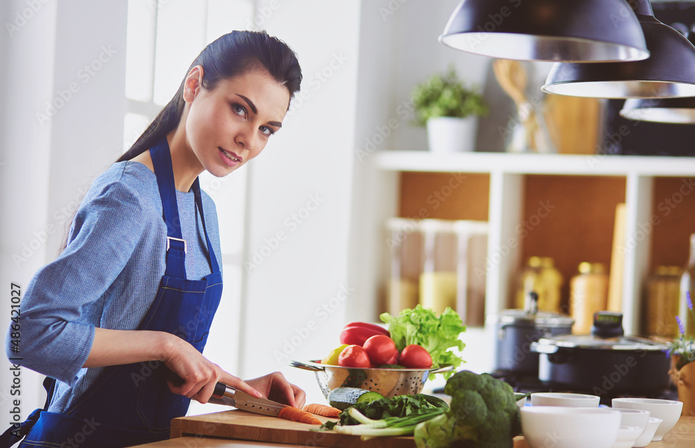 Young woman cutting vegetables in kitchen at home Young woman cutting vegetables in kitchen at home