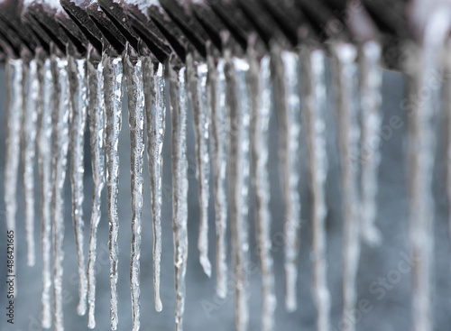 many icicles hanging from a roof with selective focus
