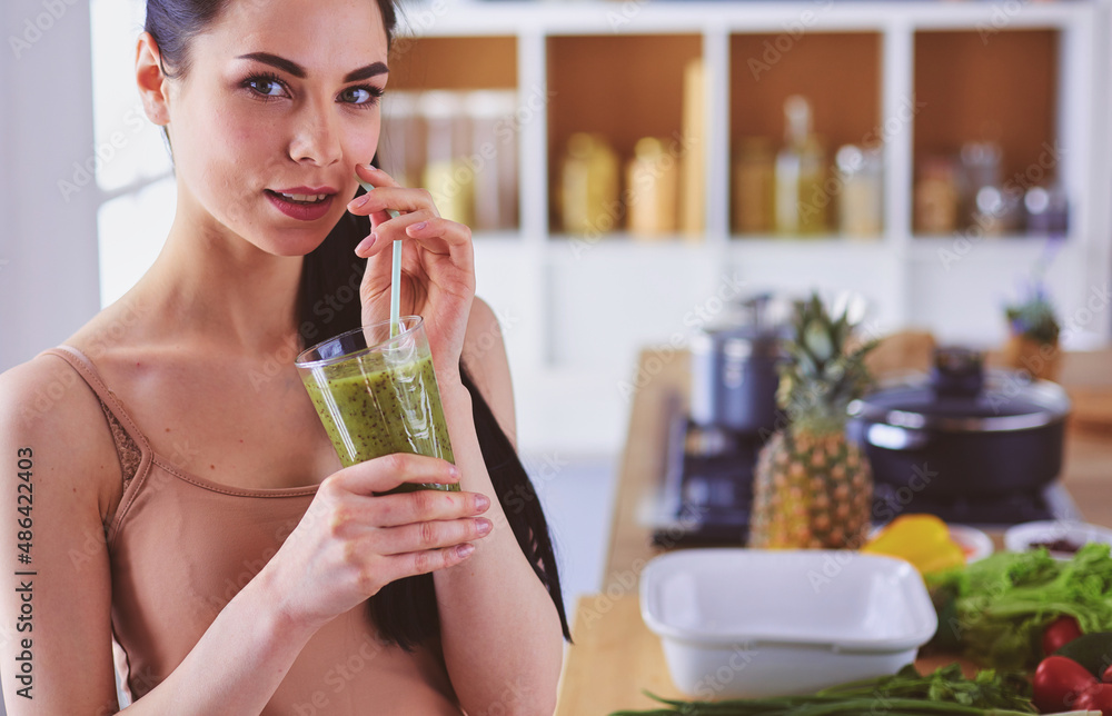 Young woman with glass of tasty healthy smoothie at table in kitchen Young woman with glass of tasty healthy smoothie at table in kitchen