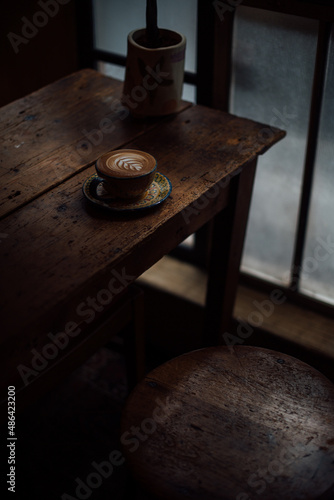 Cafe latte is on a vintage table under dramatic lighting