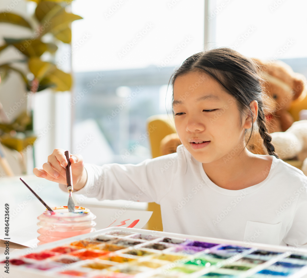 beautiful young child wear white shirt, looking water, mix color for painting on paper art. asian beautiful children happy and fun color painting education in small school beautiful young child wear white shirt, looking water, mix color for painting on paper art. asian beautiful children happy and fun color painting education in small school