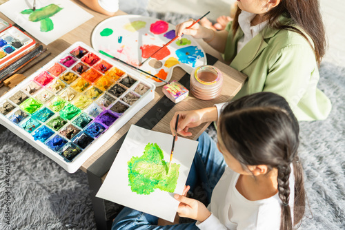 top view of beautiful young children fun painting color on paper art in education classroom, select focus at paper. asian beautiful children happy and fun color painting education in small school