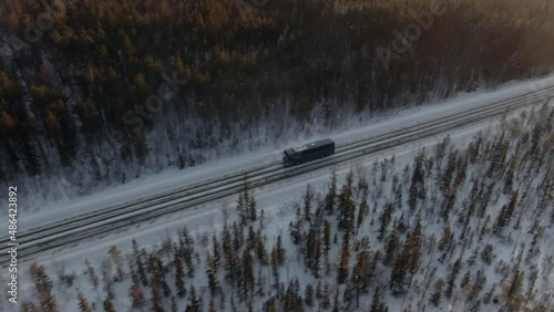 Aerial view of the highway where the bus rides, dense forest on the sides, winter time, side view, camera distance.