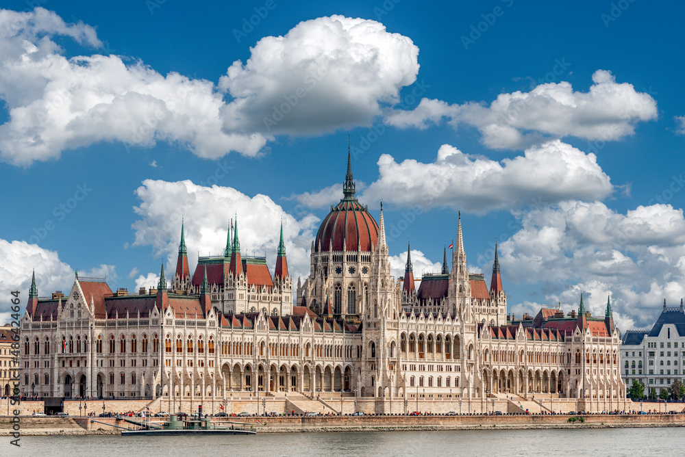Fototapeta premium Schrägansicht der Aussenfassade des ungarischen Parlamentsgebäudes in Budapest an der Donau mit blauem Himmel und Schönwetterwolken