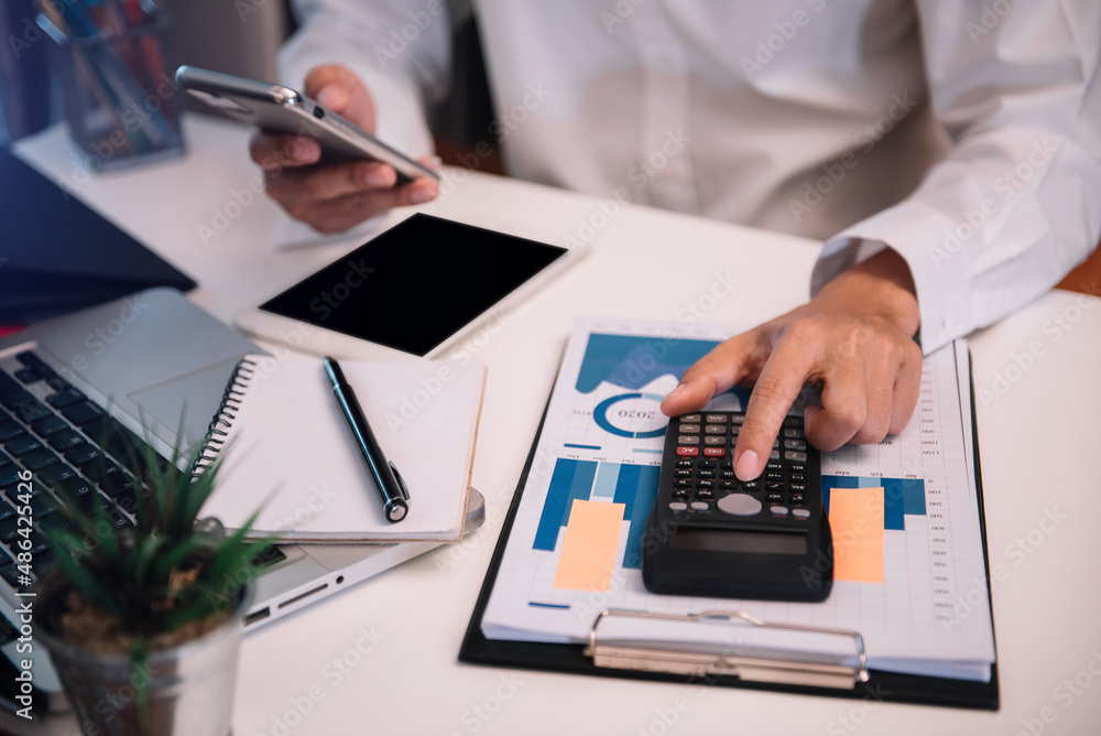 Fototapeta premium Male businessman working on desk office with using a calculator to calculate the numbers, finance accounting concept.