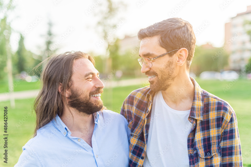 cheerful gay couple looking at each other in the park