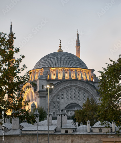 Istanbul cityscape - panoramic view of Suleymaniye Mosque in the evening with light. Traditional arabic town with silhouettes of minarets on sunset, ancient landmarks of muslim architecture in Turkey.