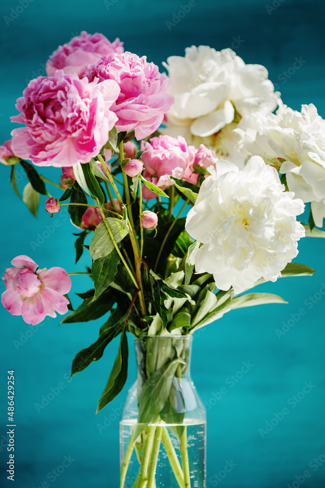Flower bouquet of pink natural peonies flowers in a vase over turquoise background Flower bouquet of pink natural peonies flowers in a vase over turquoise background