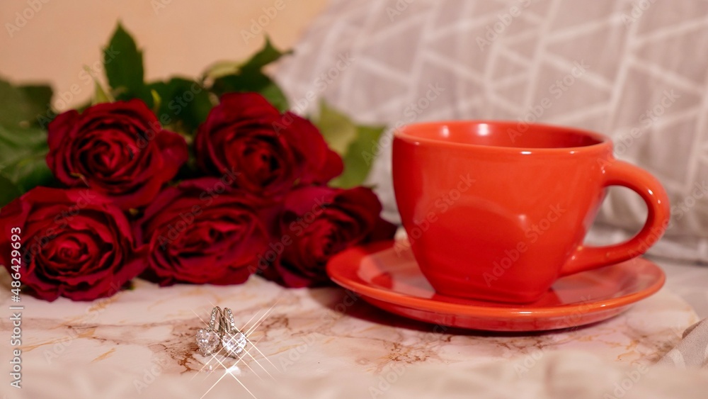 Background Festive Flatlay, composition for Valentine's Day on February 14. Coffee in a red cup, red rose flowers and diamond heart earrings at home in bed Background Festive Flatlay, composition for Valentine's Day on February 14. Coffee in a red cup, red rose flowers and diamond heart earrings at home in bed