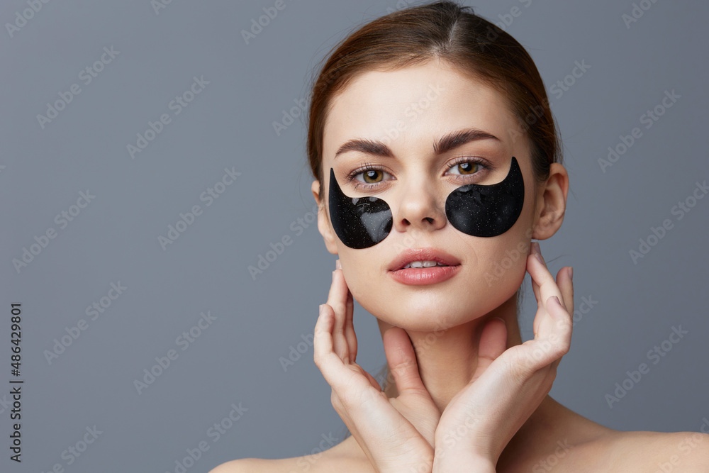 young woman with patches on the face clean skin health rejuvenation Gray background young woman with patches on the face clean skin health rejuvenation Gray background