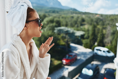 stylish woman wearing sunglasses posing in a bathrobe on a balcony rest Relaxation concept