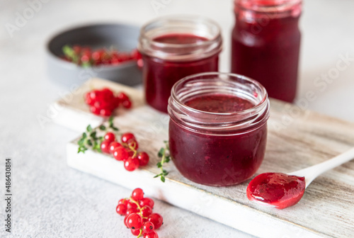 Homemade red currant jam or jelly in glass jars and red currants berries. photo
