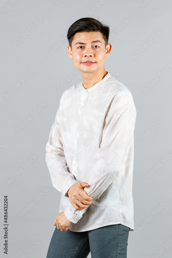 Portrait studio shot of millennial Asian smart cool handsome young male model in casual long sleeve shirt outfit standing posing smiling look at camera holding hand in jeans pocket on gray background Portrait studio shot of millennial Asian smart cool handsome young male model in casual long sleeve shirt outfit standing posing smiling look at camera holding hand in jeans pocket on gray background