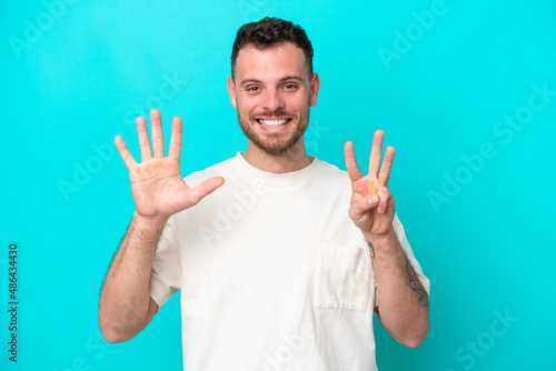 Young Brazilian man isolated on blue background counting eight with fingers